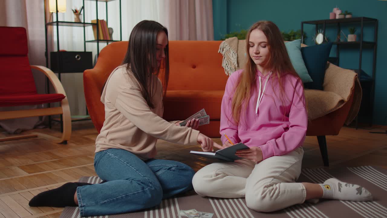 вдумчивые девушки друзья братья и сестры рассчитывают семейный бюджет в долларах наличными пишут в тетради дома