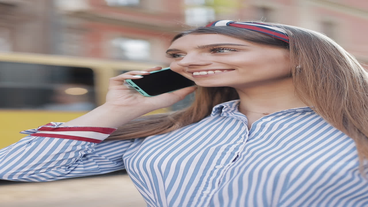 Ragazza felice che parla al telefono in una via cittadina.