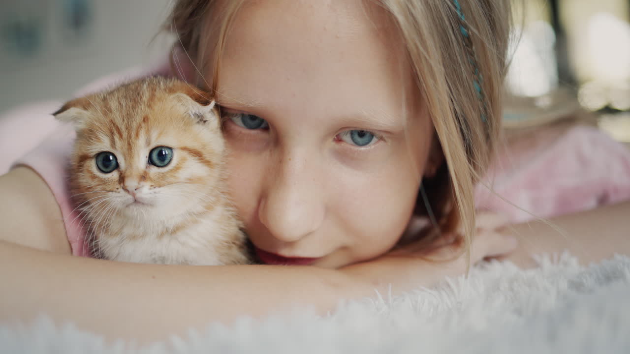 Portrait of a cute baby with a ginger kitten looking at the camera