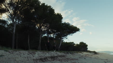 two people walk on the shore near the ocean in the morning to wake up muscles