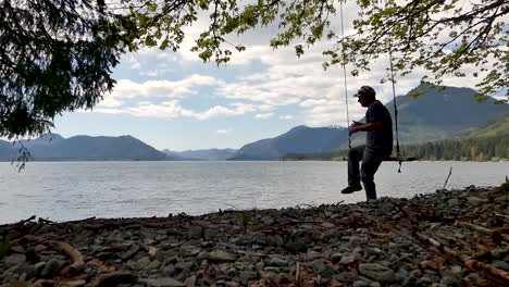 Swinging-on-rope-with-lake-and-mountains-in-the-background