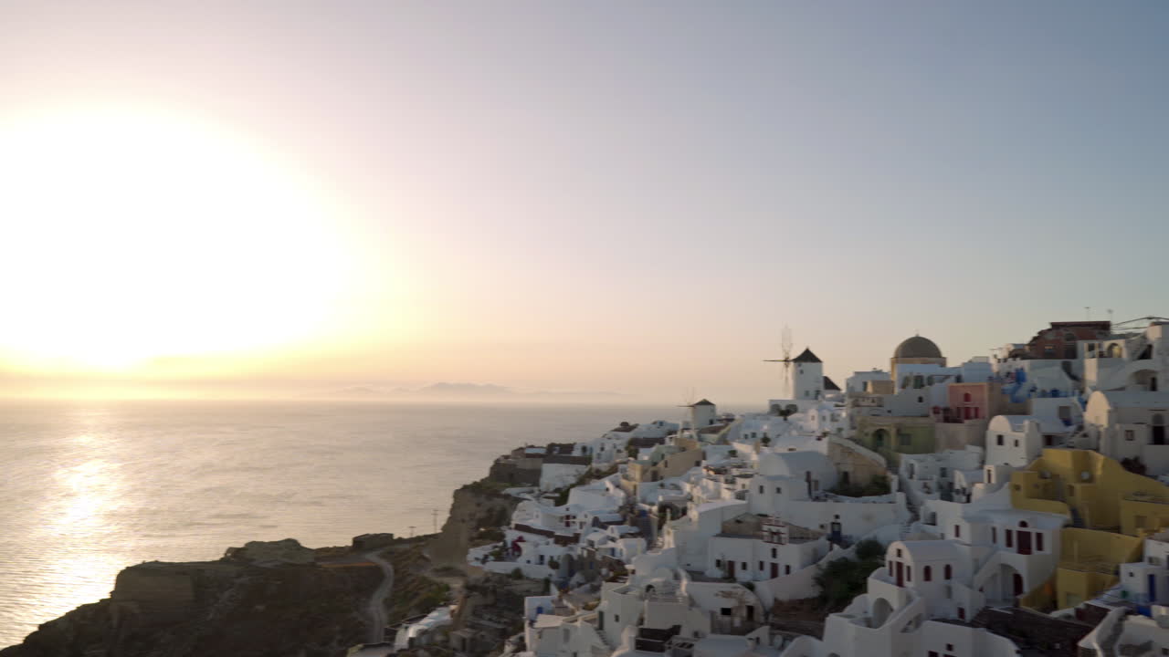 toma panorámica lenta de oia en santorini, grecia durante la puesta de sol