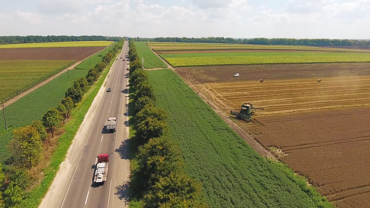 highway with cars near agricultural fields where there is harvesting