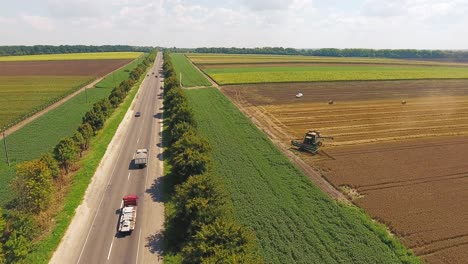 highway with cars near agricultural fields where there is harvesting