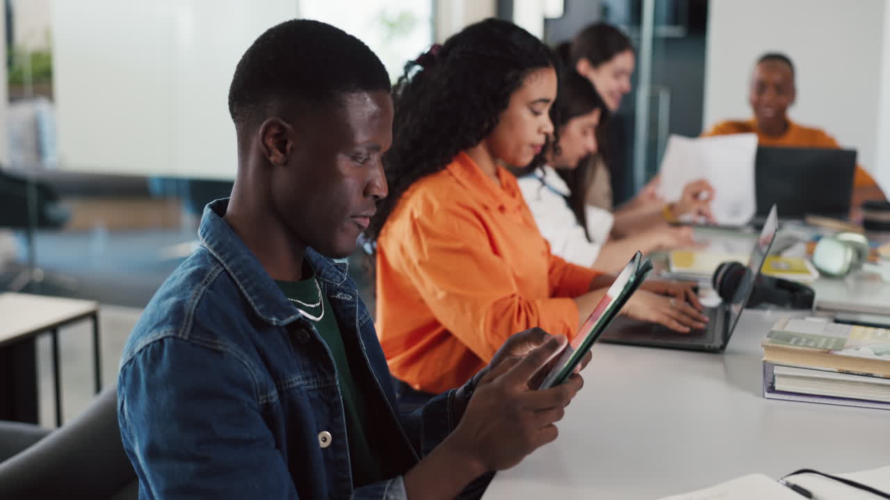 Young Man Using Tablet in a Modern Office with Colleagues