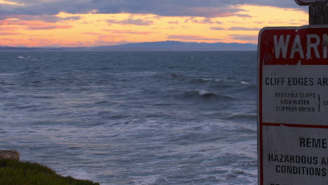 Panning-Timelapse-of-Danger-Sign-Near-Ocean-During-Evening