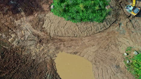 aerial top down flight over industrial construction site with working crane digging pond in sunlight