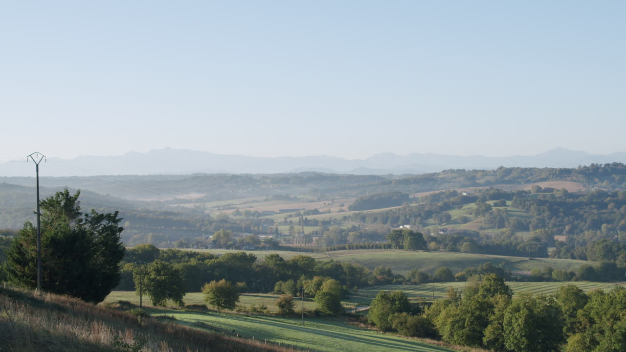 Idyllic hilly landscape in the countryside, valley with trees and mountain range in the background
