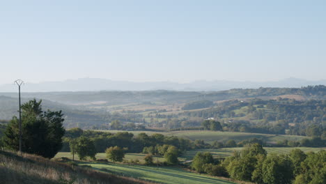 idyllic hilly landscape in the countryside, valley with trees and mountain range in the background