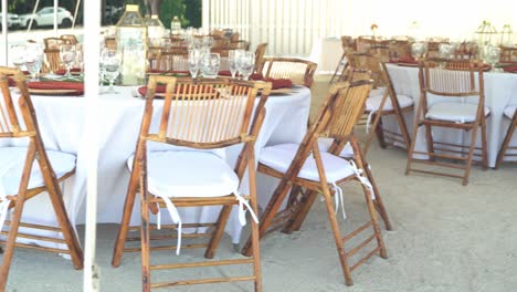 Panning shot of chairs and tables wedding venue by the beach on a sunny day with peace and tranquility outdoor seating sandy beach engagement seating with tables