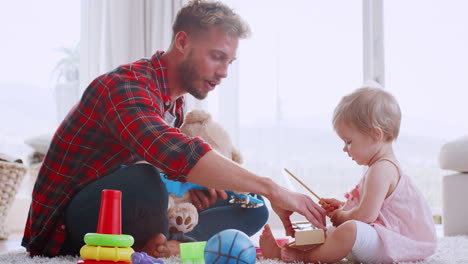 Young-dad-and-toddler-daughter-playing-at-home,-side-view