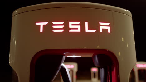 close-up night view of tesla supercharger charging station lit up red