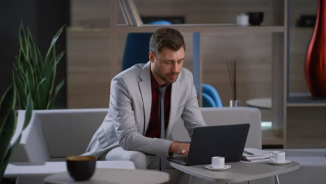 Young-businessman-working-laptop-computer-waiting-colleague-in-remote-workplace.