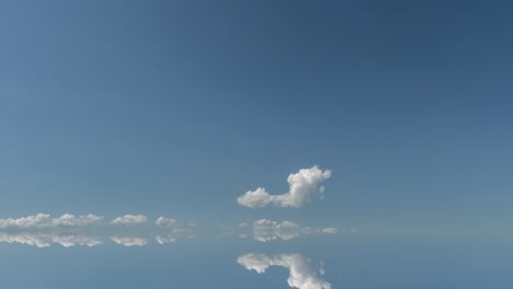 futuristic background consisting of time lapse clip of white fluffy clouds over blue sky and their reflection, video loop