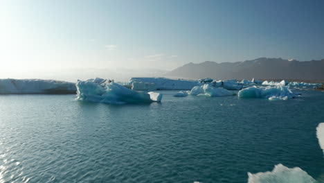 Scenic-drone-view-glacier-lagoon-in-Jokulsarlon-lake,-Iceland,-with-icebergs-floating-on-water.-Birds-eye-view-of-ice-blocks-drifting-in-Vatnajokull-lagoon-over-Breidamerkurjokull-glacier-tongue