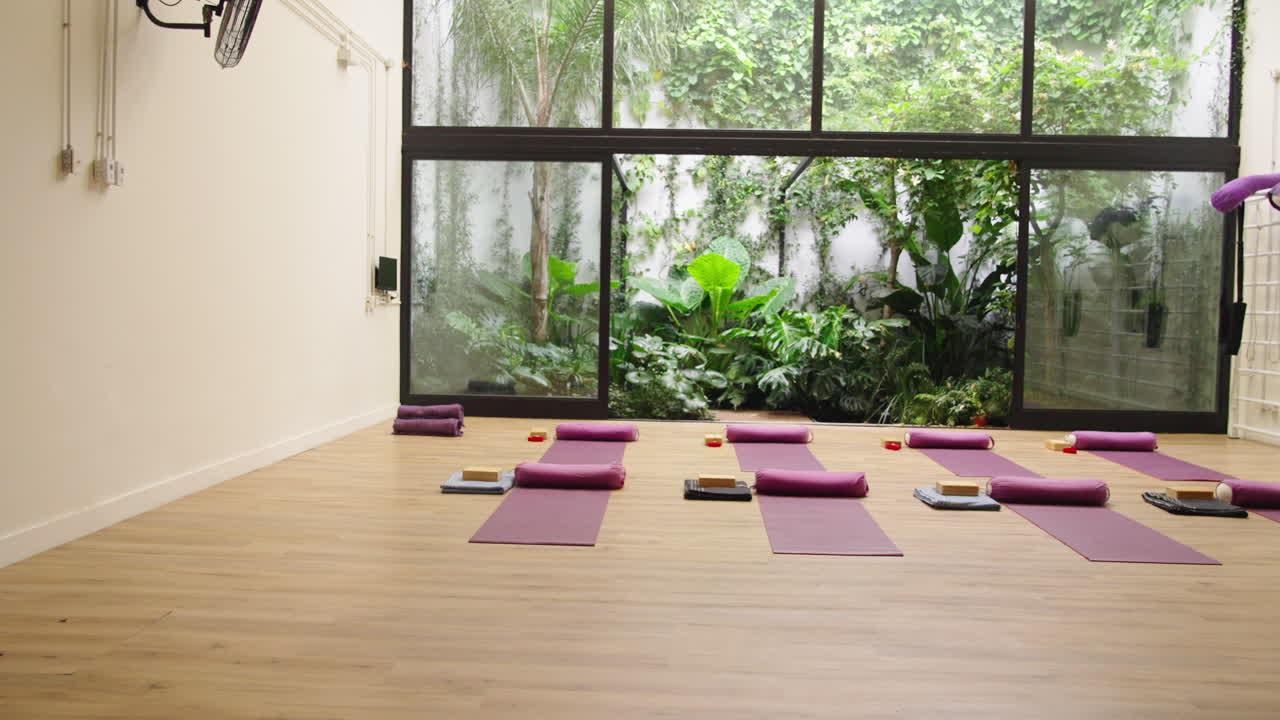 Moderne yogastudie med lilla måtter og frodig haveudsigt