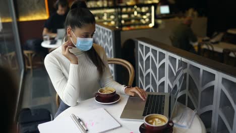 woman working on laptop in a coffee shop during pandemic