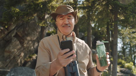 senior man hiking and using smartphone