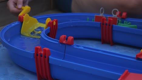 hand turning yellow lift on blue waterplay toy set