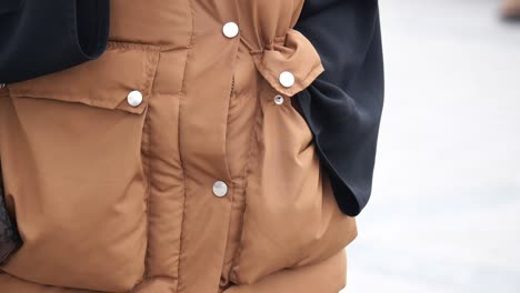 close-up of a brown puffer vest with pockets and a shoulder bag