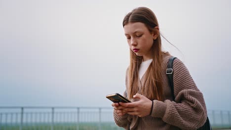 teenage girl texting on smartphone outdoors