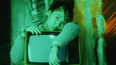 portrait of beautiful asian fashion model with retro tv in studio