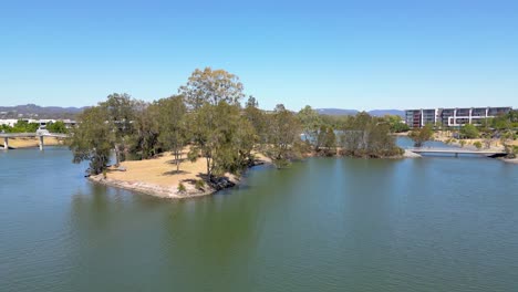 Drone-Volando-Hacia-El-Oeste-A-Través-Del-Lago-Orr-En-Varsity-Lakes-En-Queensland,-Australia,-Con-El-Interior-Al-Fondo