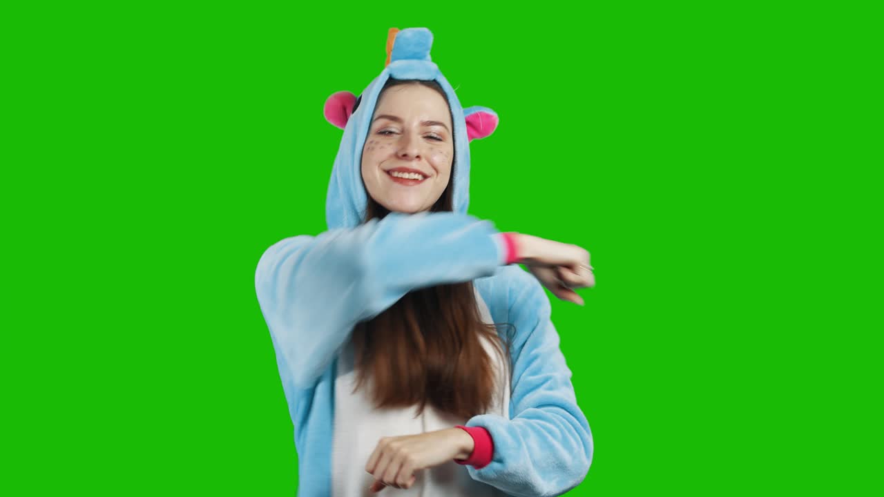 크롬 키 녹색 배경에 아름다운 유니콘 의상을 입은 사랑스러운 젊은 갈색 소녀의 초상화. 웃고 놀고. 의상을 입고 있는 애니메이터. 유니콘 잠옷. 알파 채널과 함께 4k 비디오.