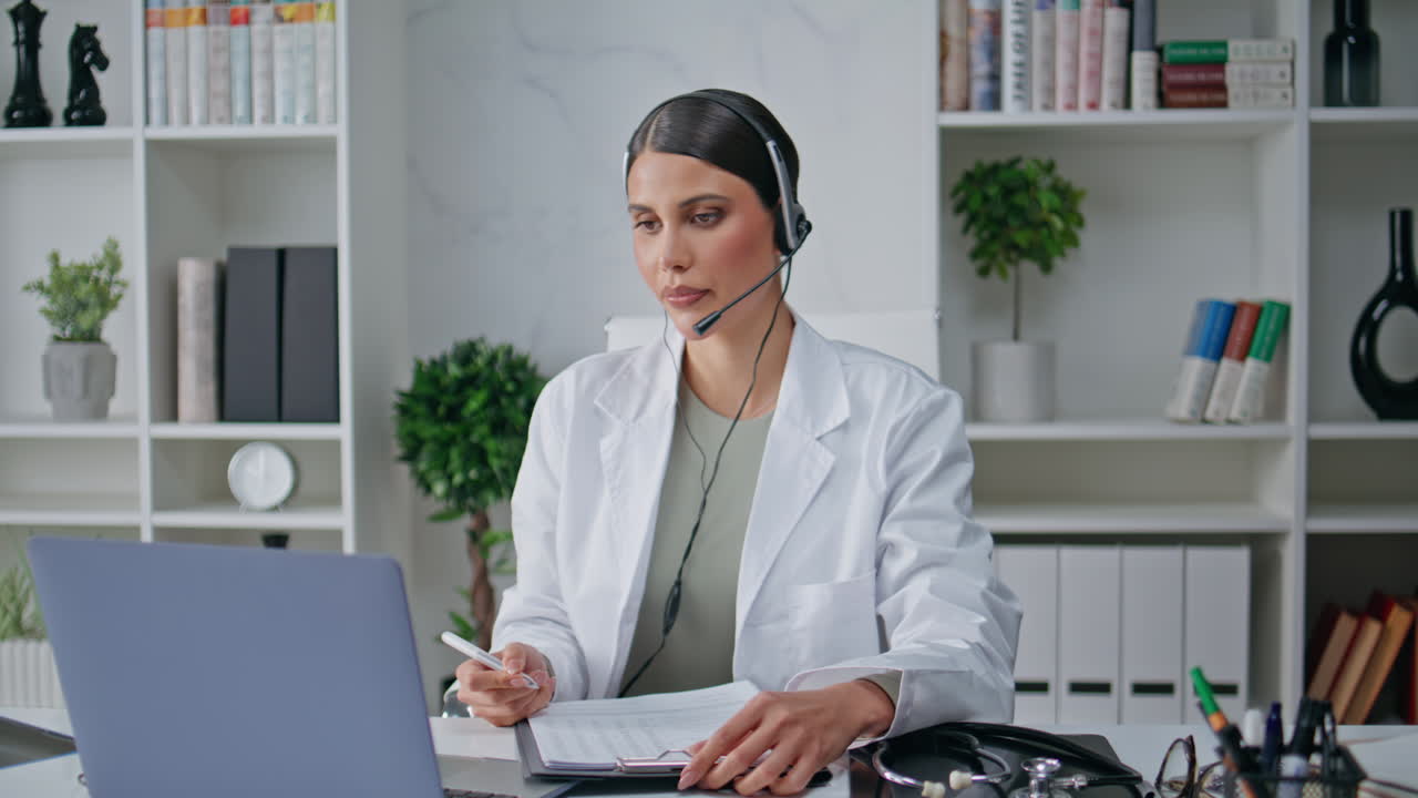 Consulente che fornisce servizi di telemedicina con cuffie che scrive appunti in primo piano