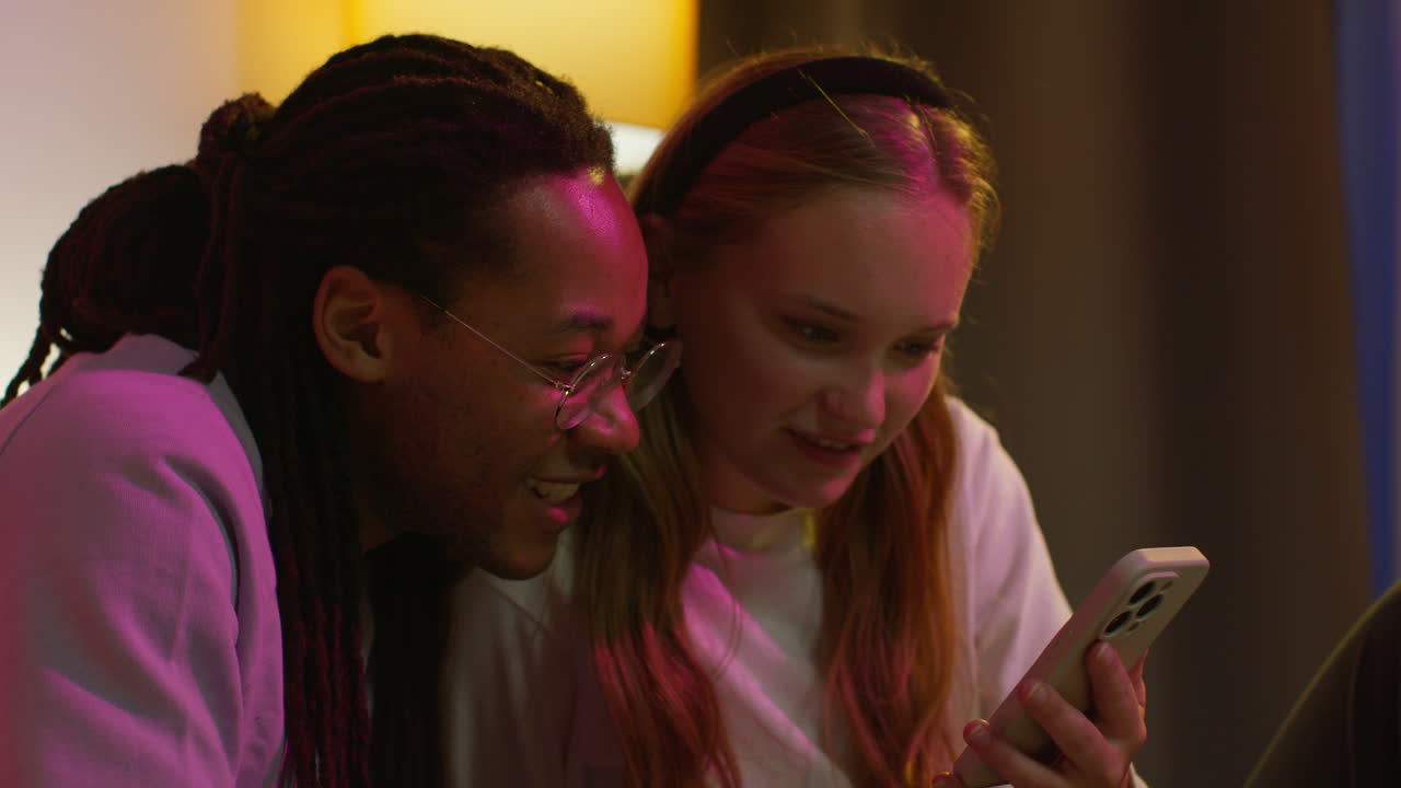 una pareja se ríe juntos mientras miran su teléfono