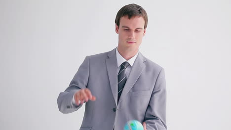 serious businessman playing with a small globe