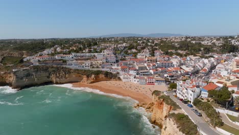 orange roof white wall home villas houses and turquoise water crashing on sandy beach, carvoeiro village algarve