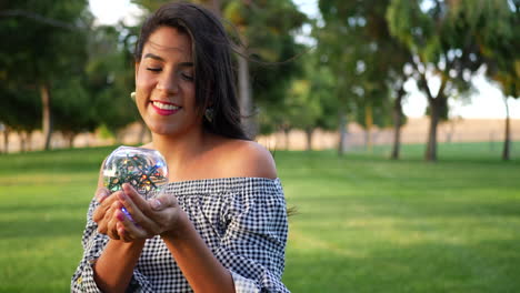 una linda mujer hispana sonriendo alegremente y caminando en un parque con una bola de cristal mágica