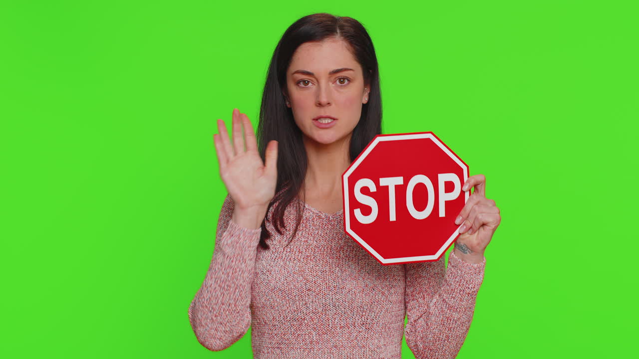 mujer sosteniendo una señal de parada frente a la pantalla verde