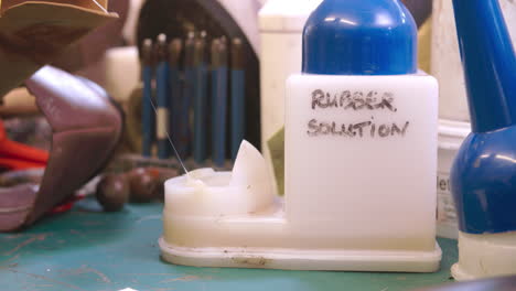 close up of shoemaker applying rubber solution glue to shoe