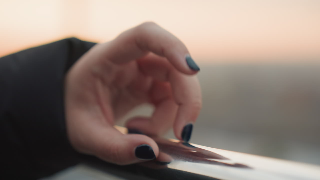 Coreografia di mani a distanza ravvicinata su un tetto al tramonto. Scatto dettagliato delle dita che danzano sulla ringhiera all'ora d'oro. Primo piano della mano che esegue una danza delicata sulla ringhiera del tetto sotto il caldo bagliore del tramonto.