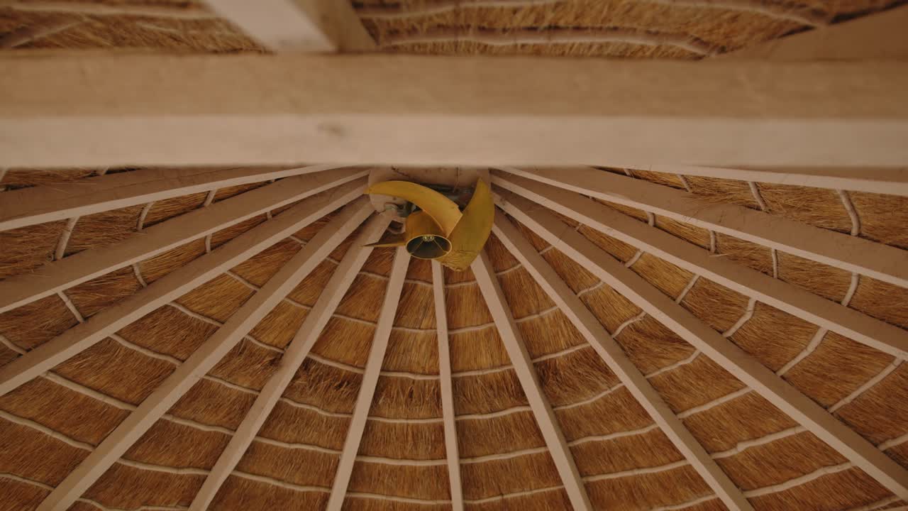 primer plano del techo de un gazebo paraguayo con techo de paja, hecho de paja y madera, con un ventilador en el medio para enfriarse en los días calurosos