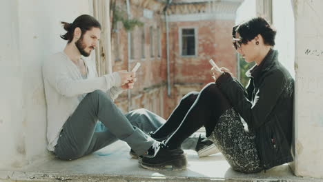 Young-Hipster-Couple-Sitting-At-The-Window-Use-Mobile-Phones-Concept---The-Lack-Of-Live-Communicatio