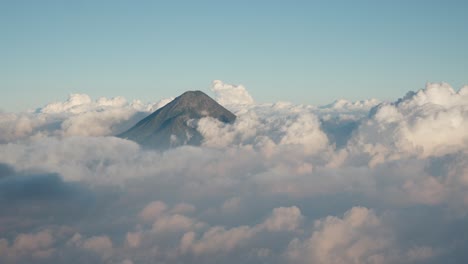las torres del volcán agua por encima de las nubes cumulus al atardecer, proyectando un suave resplandor