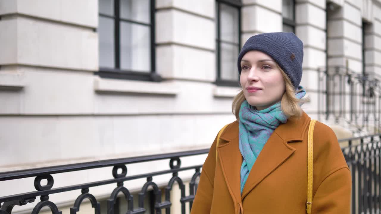 Giovane donna caucasica felice, allegra, positiva e rilassata che cammina per una strada di Londra e sorride