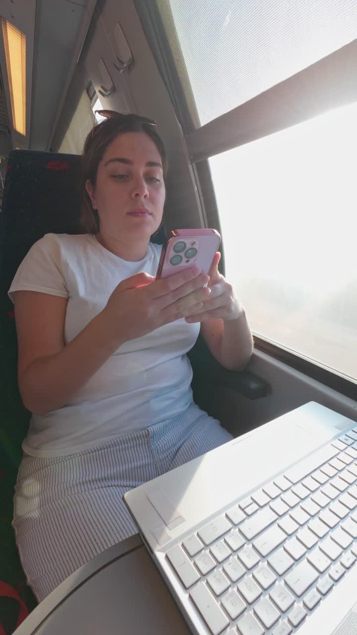 Woman Multitasking Between Laptop and Phone on a Train