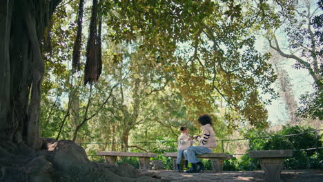woman sitting bench child at family weekend. mom daughter playing game.