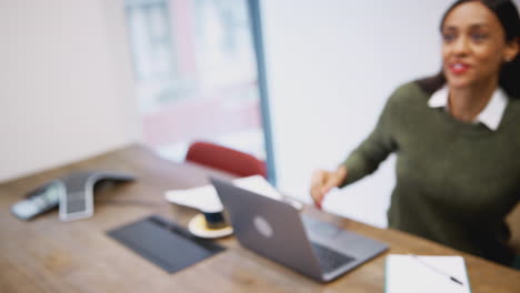businesswoman shaking hands with male job candidate in meeting room before interview