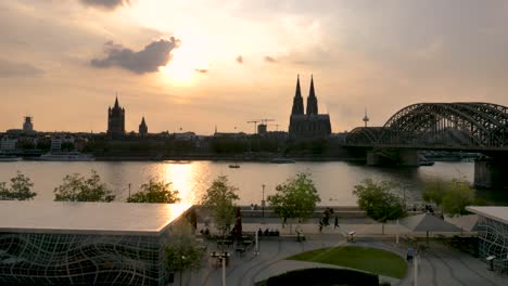 La-Catedral-Del-Horizonte-De-Colonia,-El-Puente-Hohenzollern-Y-La-Torre-Colonius-Al-Atardecer-En-Alemania,-Toma-Amplia-De-Aceleración-Bloqueada