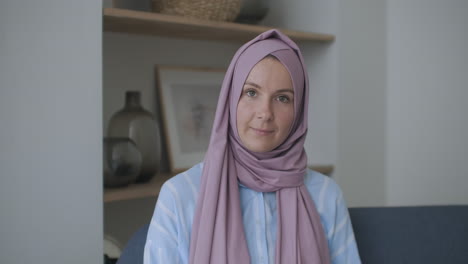 looking at the camera and nodding her head a muslim woman in a hijab is talking on a video link and listening to a lecture. remote video conversation