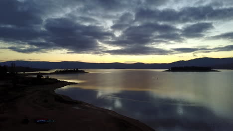 sunset over the calm waves and landscape of jindabyne, australia -aerial ascend