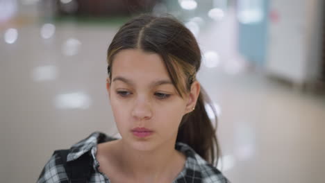 una joven confiada camina por un centro comercial moderno, bebiendo jugo con una expresión enfocada y decidida, se mueve con propósito mientras lleva una camisa a cuadros y bebe de una pajita