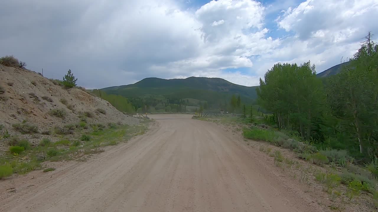 pov a través de la ventana trasera mientras conduce por un estrecho camino de grava en el paso de montaña en las montañas rocosas de colorado, ee.uu.