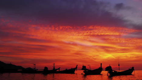 Aerial-shot-of-Koh-Tao-island,-colourful-sunset-at-the-beach-with-many-boats-floating,-Thailand