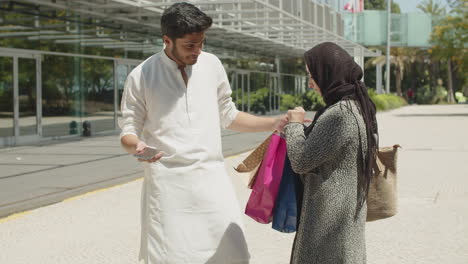 muslim man meeting his wife after shopping, helping with bags.